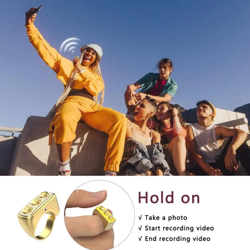 Group of people sitting outdoors with a person in yellow taking a selfie, featuring a gold ring with recording features.