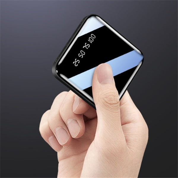 Hand holding a small rectangular device with a digital display on a dark background