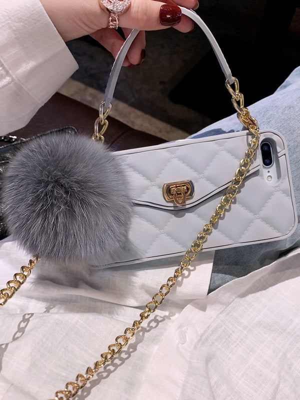 White quilted handbag with gold chain strap and gray fur pom-pom accessory.