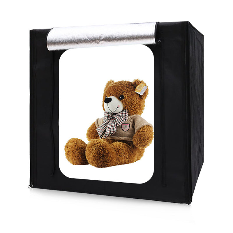 Teddy bear inside a photo studio light box on a white background