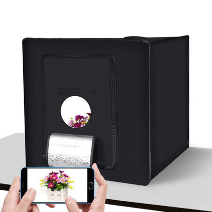 Black photo studio box with a smartphone and floral arrangement on a white background