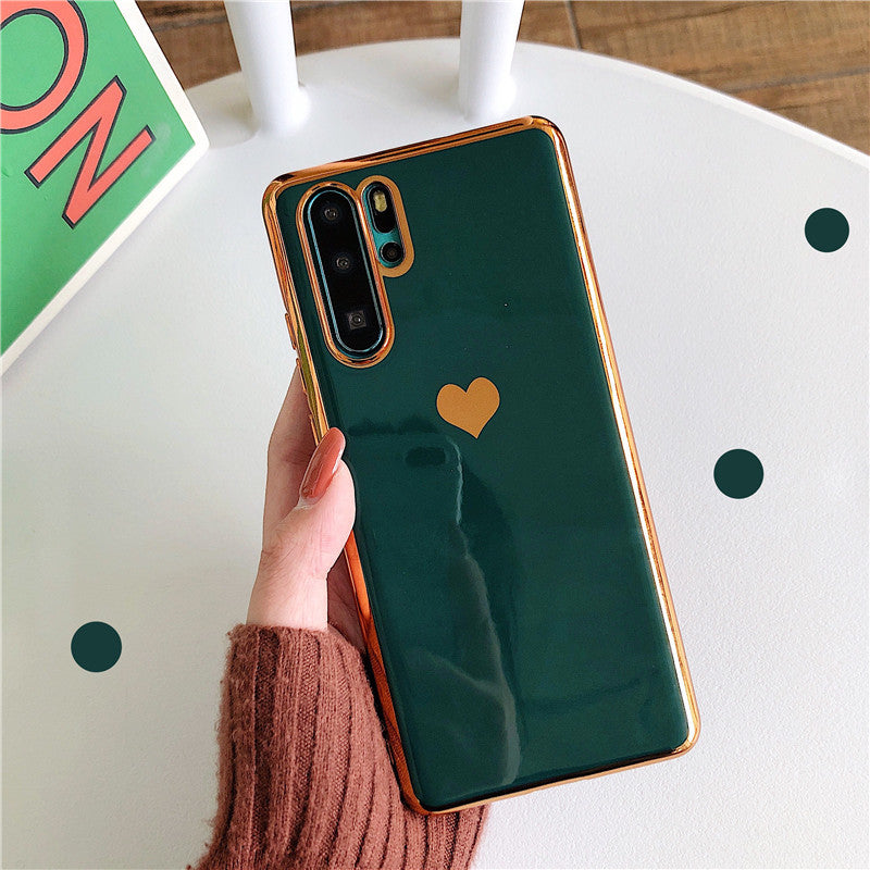 Green phone case with a heart design held by a hand on a white surface.