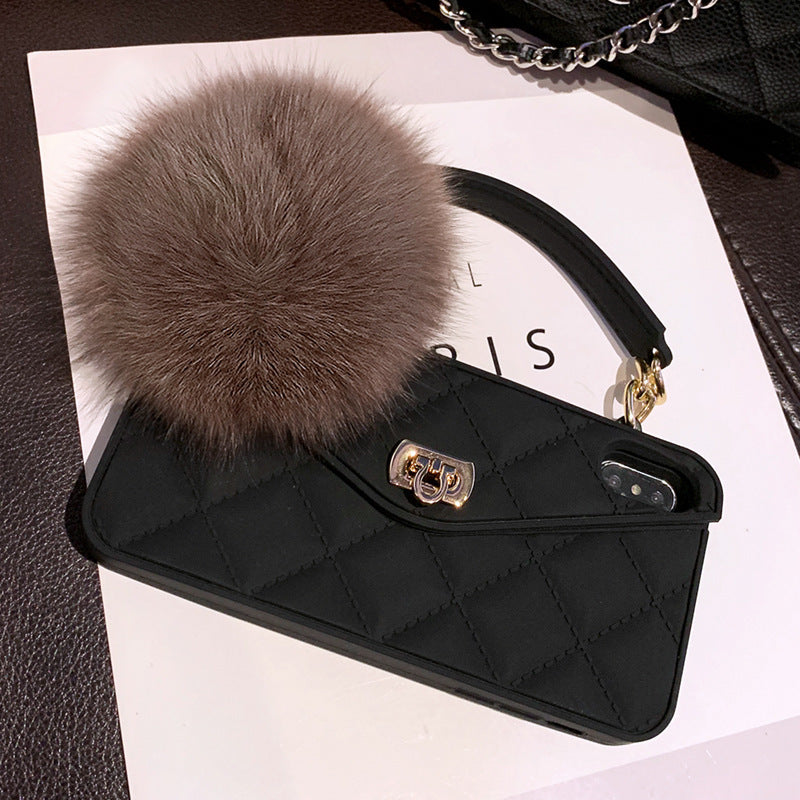 Black quilted phone case with fur pom-pom and chain on a white surface