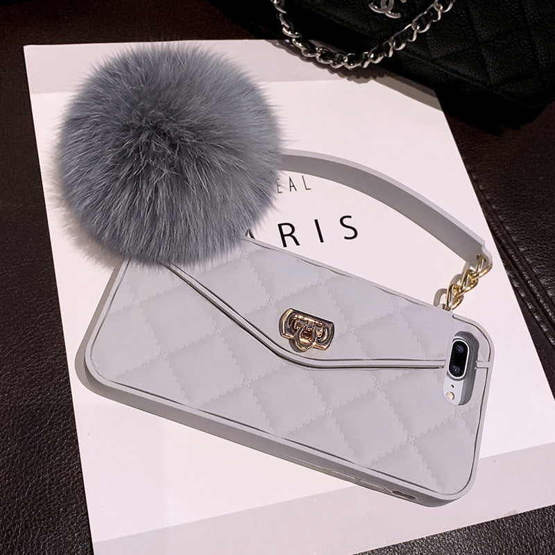 Phone case with fur pom-pom and chain on a white surface