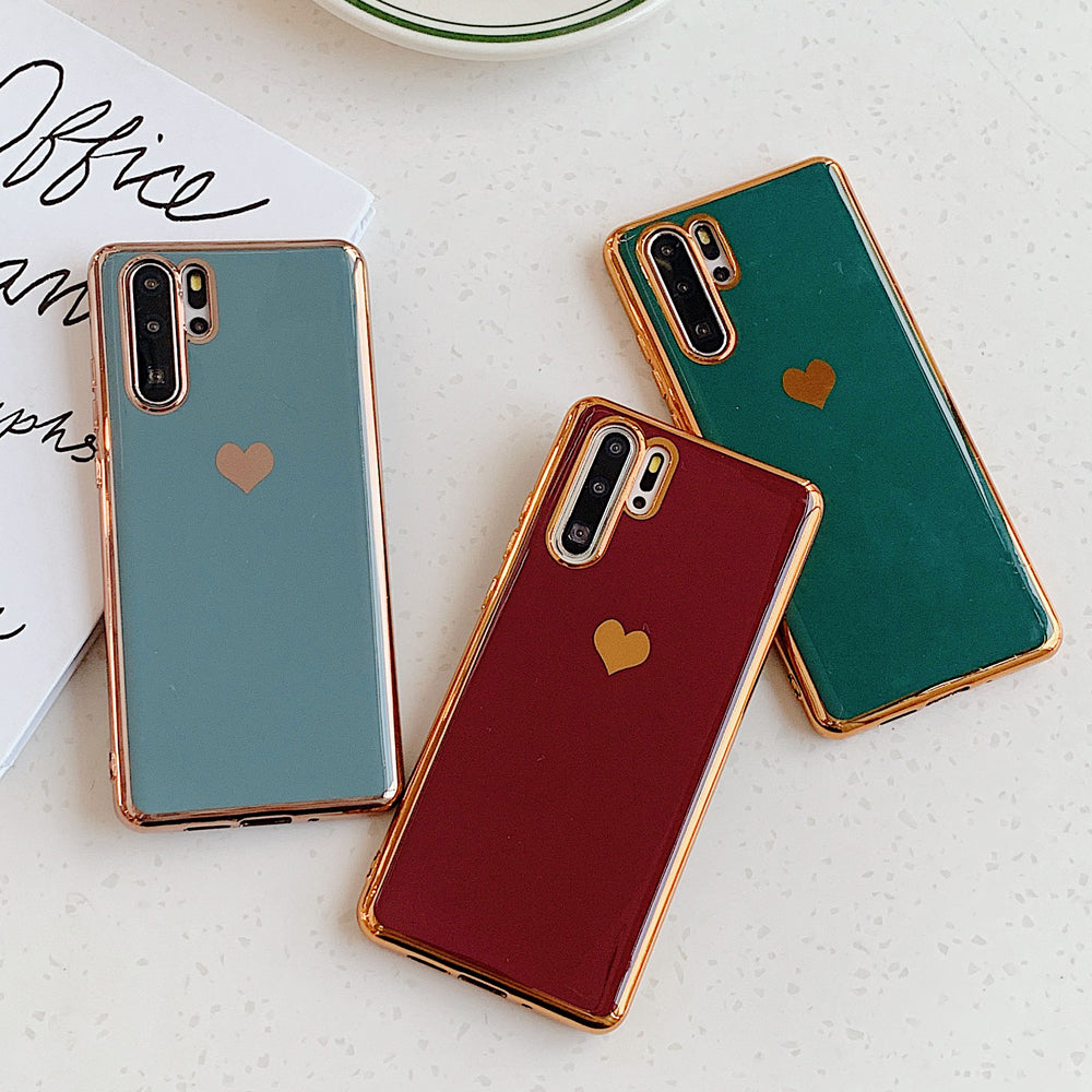 Three phone cases with heart designs on a light surface