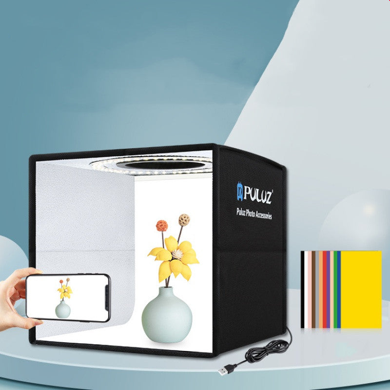 PULUZ photo studio light box with a smartphone and floral arrangement on a blue background