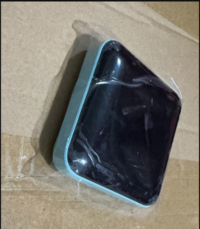 Black rectangular object in a clear plastic bag on brown cardboard